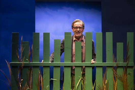 Christoph Reiche hinter einen grünen Gartenzaun stehend