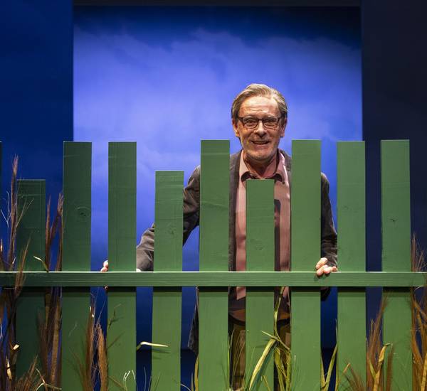Christoph Reiche hinter einen grünen Gartenzaun stehend