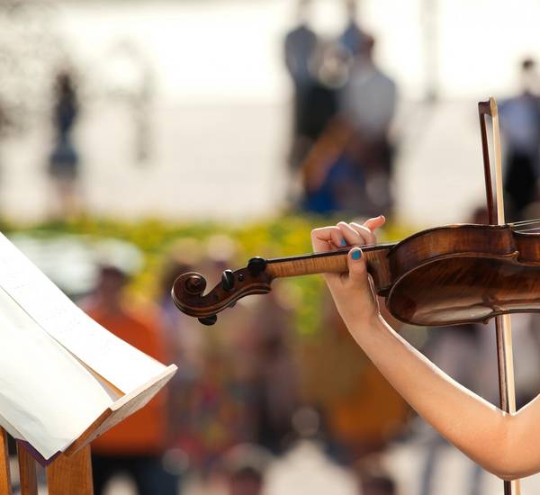 Eine Violine in der Hand eines Menschen mit lackierten Fingernägeln